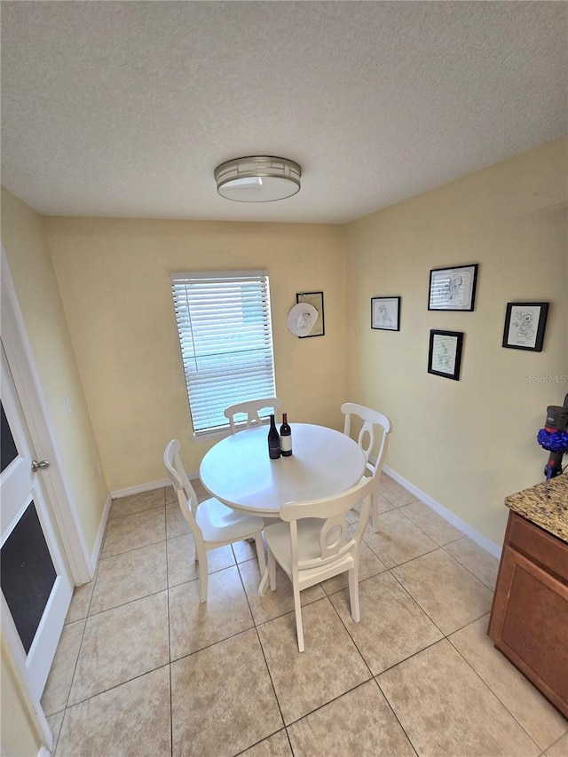 dining area featuring light tile patterned floors, a textured ceiling, and baseboards