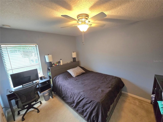 bedroom featuring a ceiling fan, light carpet, a textured ceiling, and baseboards