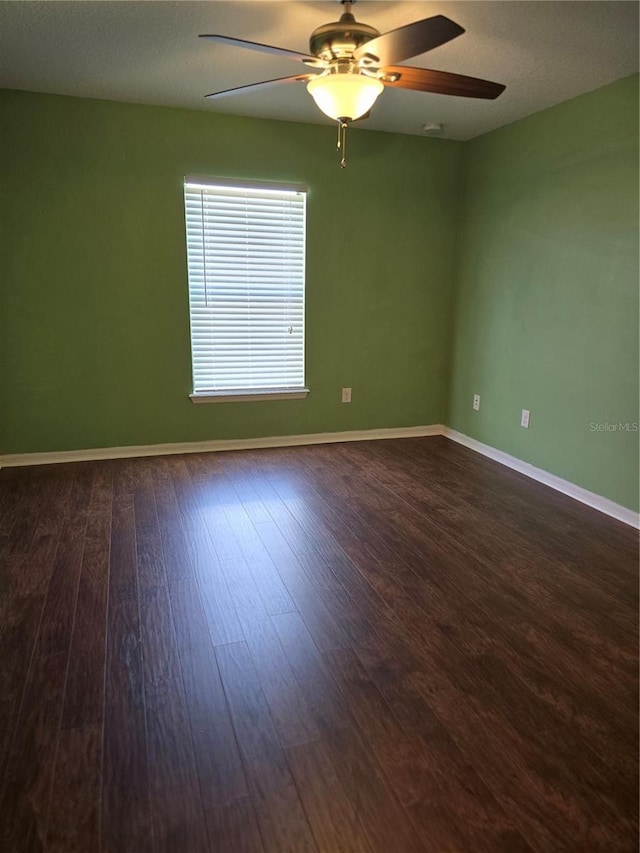 empty room with ceiling fan, baseboards, and dark wood finished floors