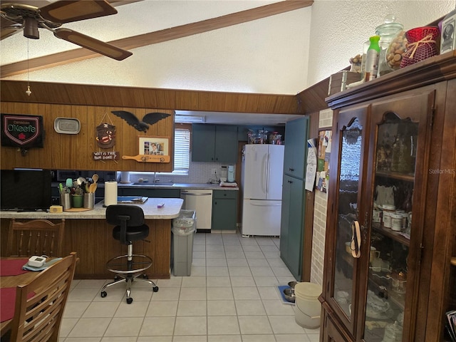 kitchen with lofted ceiling, a breakfast bar area, white refrigerator, stainless steel dishwasher, and kitchen peninsula