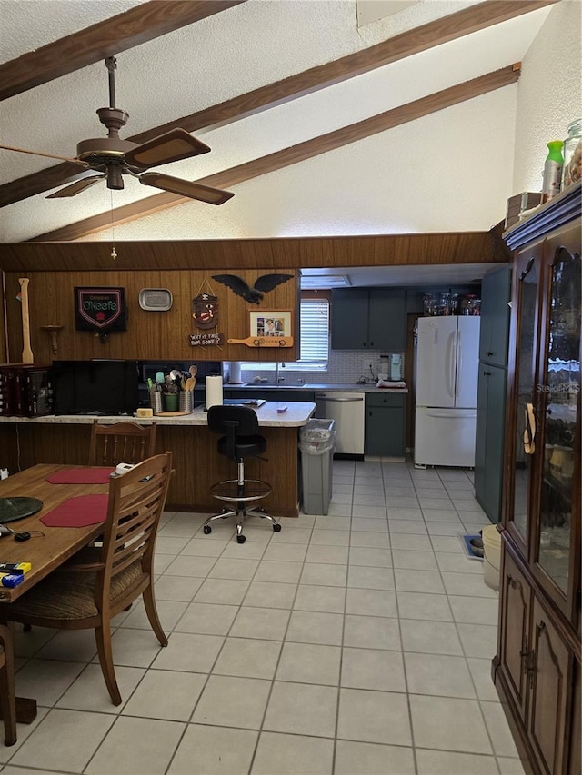 kitchen featuring dishwasher, white fridge, vaulted ceiling with beams, and light tile patterned floors