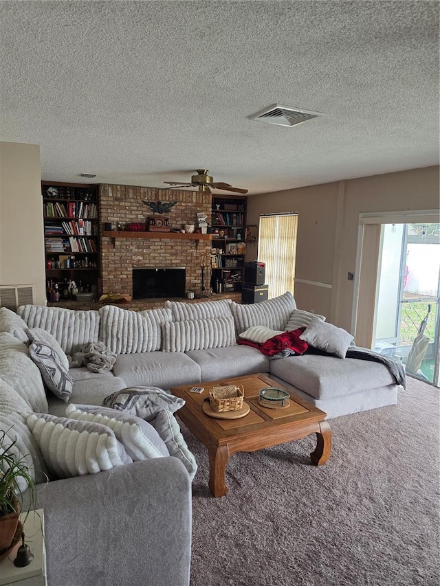 living room featuring ceiling fan, carpet, a brick fireplace, and a textured ceiling