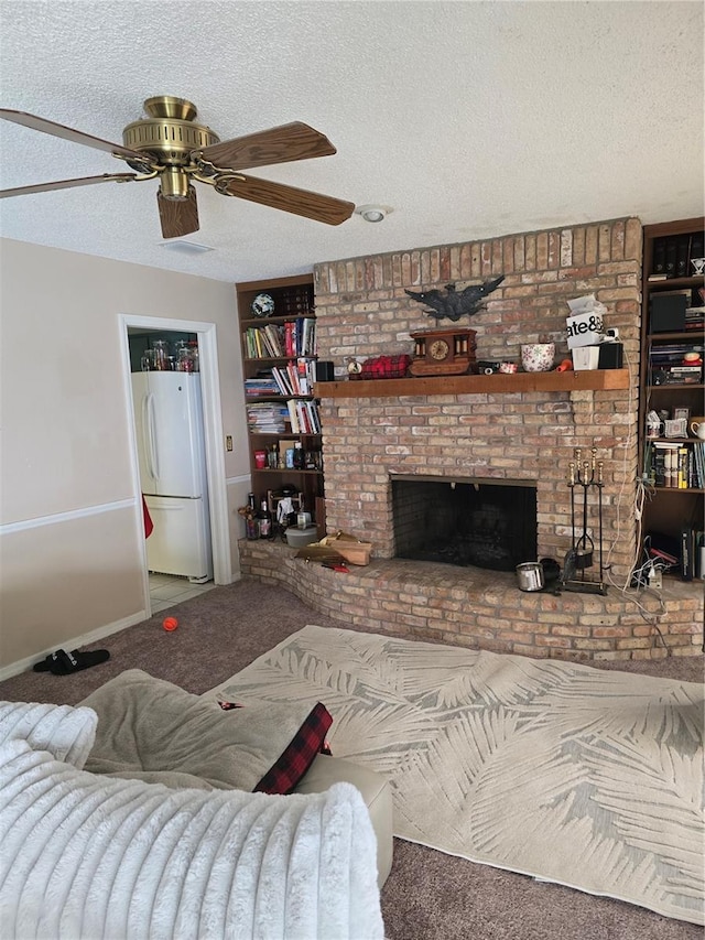 carpeted living room featuring a brick fireplace, a textured ceiling, and ceiling fan