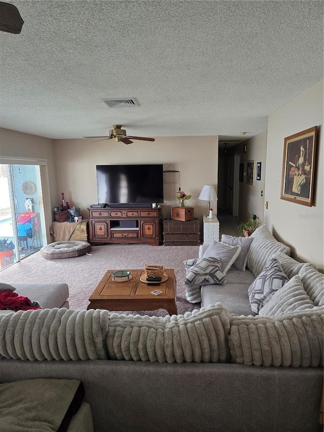 living room featuring ceiling fan, a textured ceiling, and carpet flooring