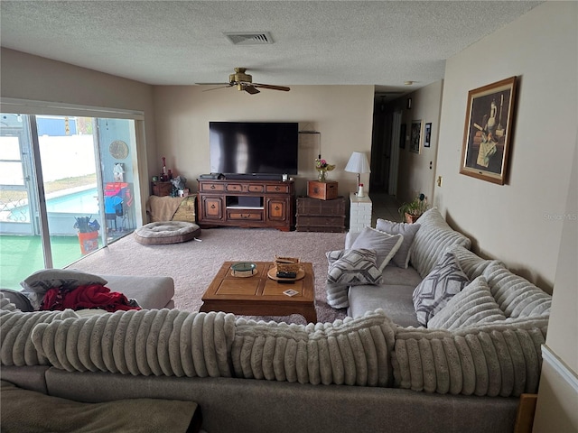 carpeted living room with ceiling fan and a textured ceiling