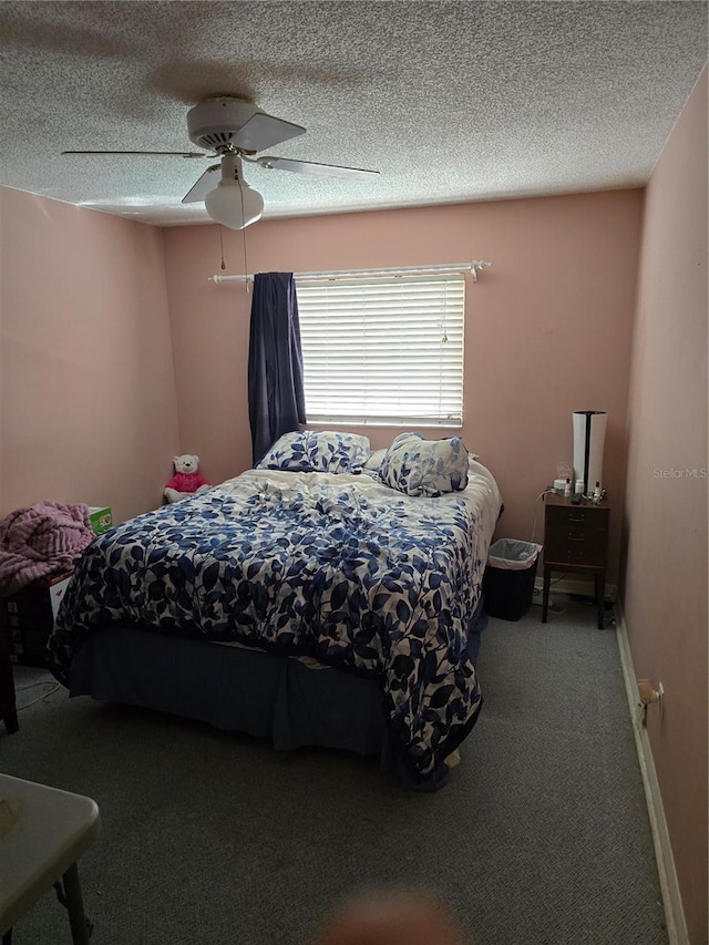 bedroom with ceiling fan, carpet floors, and a textured ceiling