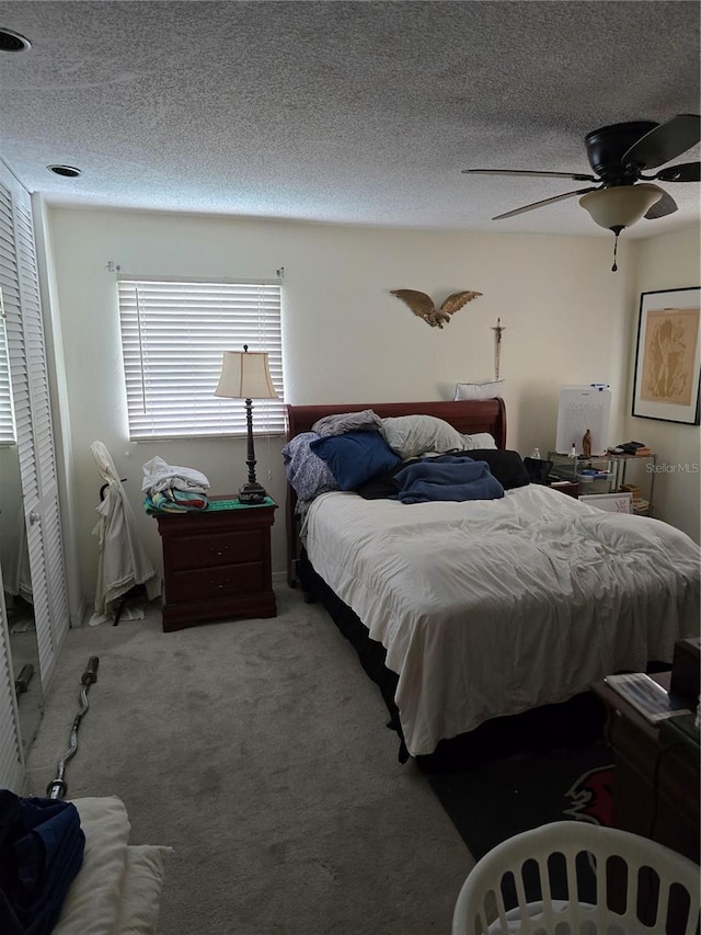 bedroom with a textured ceiling, carpet floors, a closet, and ceiling fan