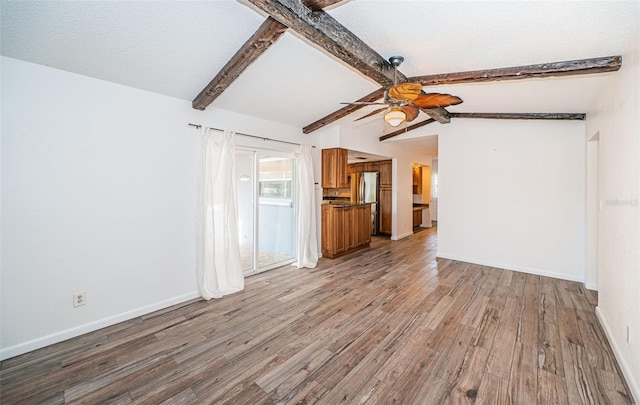 unfurnished living room with a textured ceiling, lofted ceiling with beams, ceiling fan, and light wood-type flooring