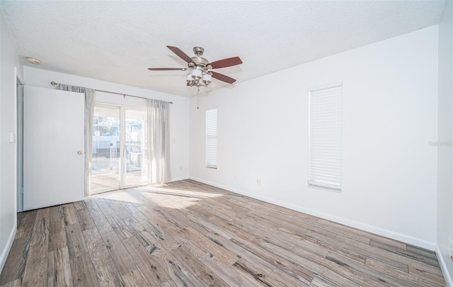 empty room with ceiling fan, light hardwood / wood-style flooring, and a textured ceiling