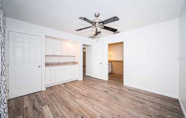 interior space featuring white cabinetry, ceiling fan, light hardwood / wood-style floors, and a textured ceiling