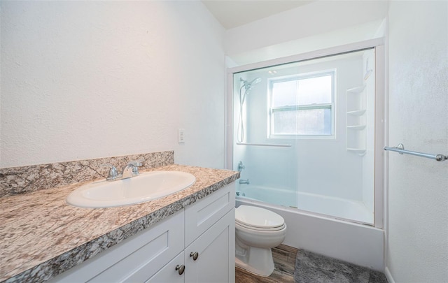 full bathroom featuring vanity, hardwood / wood-style floors, bath / shower combo with glass door, and toilet