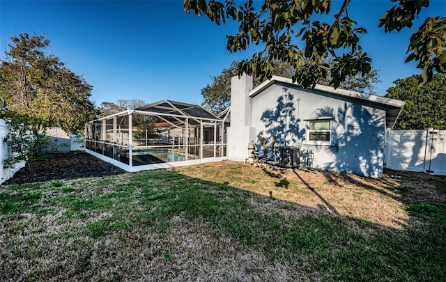 back of property featuring a fenced in pool, a yard, central AC, and glass enclosure