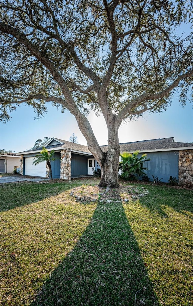 ranch-style home featuring a garage and a front lawn