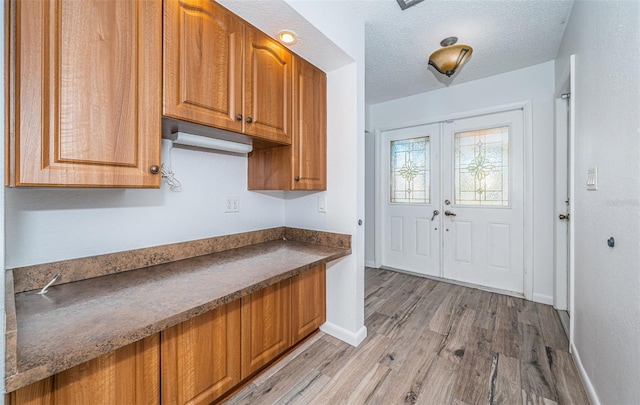 interior space featuring french doors, light hardwood / wood-style floors, and a textured ceiling