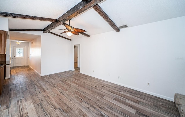 unfurnished living room with vaulted ceiling with beams, hardwood / wood-style flooring, a textured ceiling, and ceiling fan