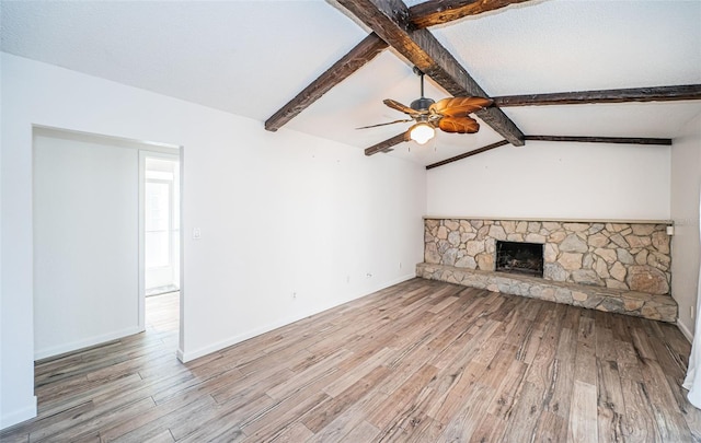 unfurnished living room with a fireplace, lofted ceiling with beams, ceiling fan, and light wood-type flooring