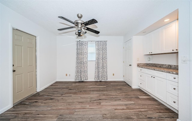 kitchen featuring white cabinetry, dark hardwood / wood-style floors, a textured ceiling, and dark stone countertops