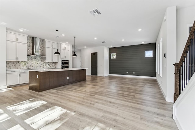 441 42nd Ave NE, Saint Petersburg, FL 33703 - kitchen featuring wall chimney range hood, recessed lighting, light countertops, a large island with sink, and light wood finished floors