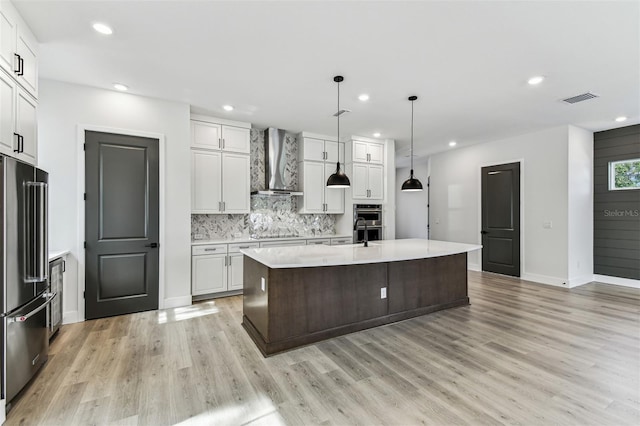 441 42nd Ave NE, Saint Petersburg, FL 33703 - kitchen with wall chimney exhaust hood, appliances with stainless steel finishes, light countertops, recessed lighting, and light wood-type flooring