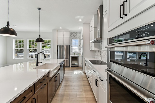 441 42nd Ave NE, Saint Petersburg, FL 33703 - kitchen with appliances with stainless steel finishes, wine cooler, wall chimney range hood, light countertops, and light wood finished floors