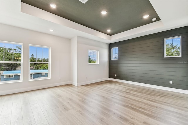 441 42nd Ave NE, Saint Petersburg, FL 33703 - spare room featuring a tray ceiling, light wood-style floors, recessed lighting, and wood walls
