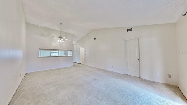 carpeted empty room featuring a textured ceiling, vaulted ceiling, and ceiling fan