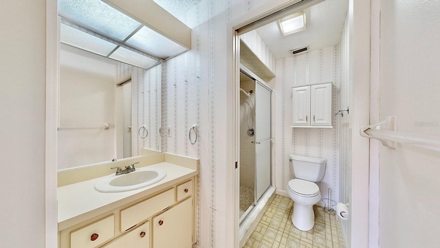 bathroom with vanity, toilet, a shower with door, and a textured ceiling