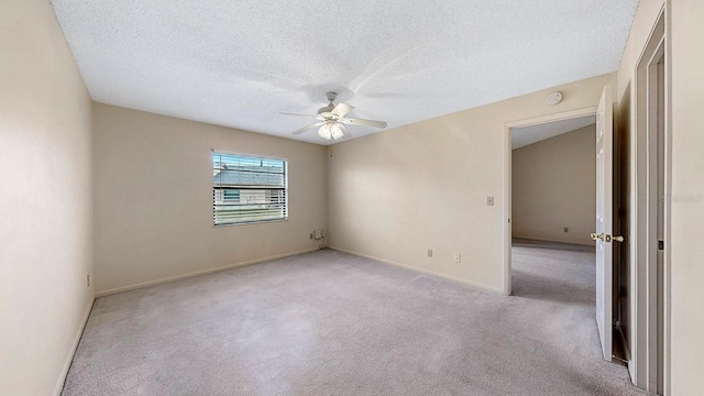 empty room with ceiling fan, light colored carpet, and a textured ceiling