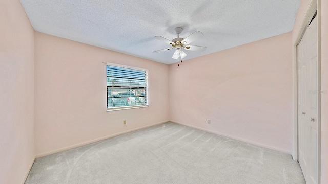 spare room featuring light colored carpet, a textured ceiling, and ceiling fan