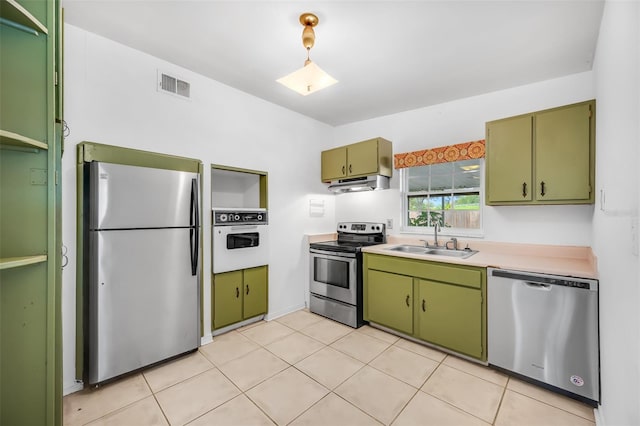 kitchen featuring sink, light tile patterned floors, stainless steel appliances, and green cabinetry