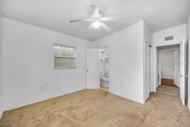 unfurnished bedroom featuring connected bathroom, light colored carpet, a closet, and ceiling fan