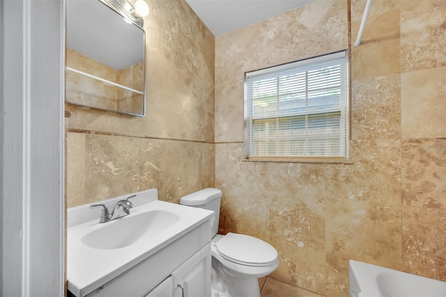 bathroom featuring vanity, tile walls, and toilet