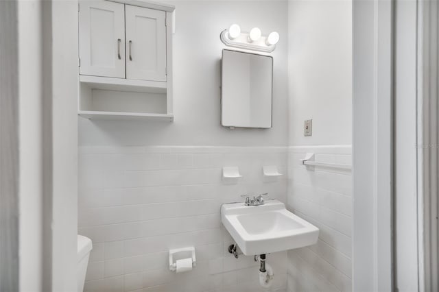 bathroom featuring sink, tile walls, and toilet