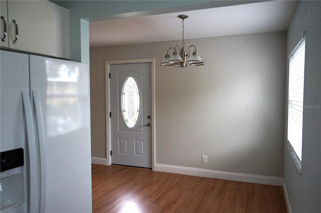 foyer entrance featuring hardwood / wood-style floors, plenty of natural light, and a chandelier