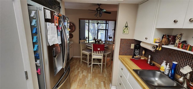 kitchen with sink, white cabinetry, backsplash, stainless steel refrigerator with ice dispenser, and light wood-type flooring