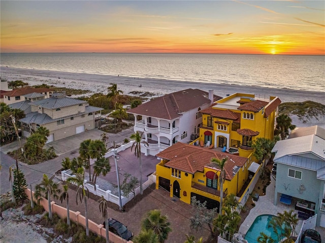 aerial view at dusk with a water view and a view of the beach