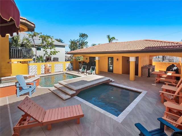 view of swimming pool with an in ground hot tub, an outdoor kitchen, and a patio area