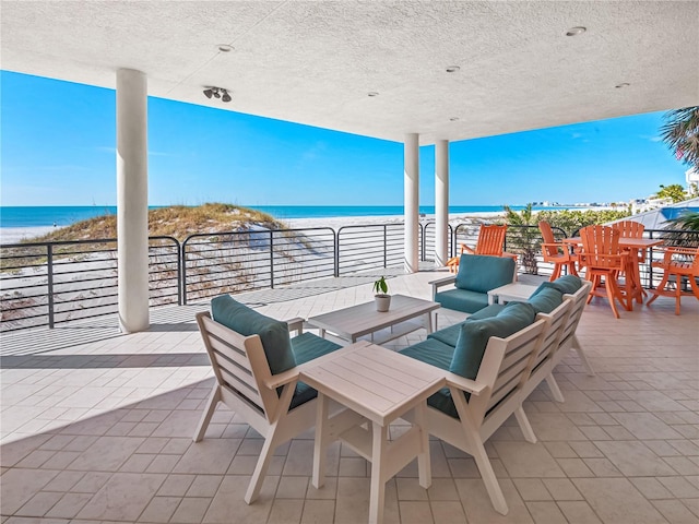 view of patio with an outdoor living space, a water view, and a view of the beach