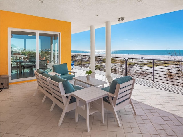 view of patio / terrace with a water view, a balcony, a view of the beach, and outdoor lounge area