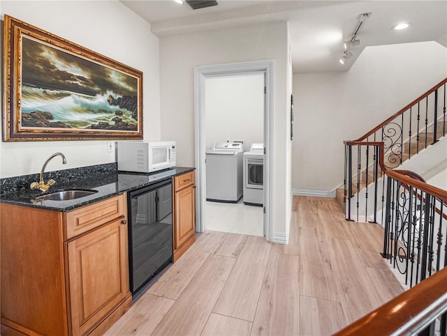 kitchen featuring wine cooler, sink, light hardwood / wood-style flooring, independent washer and dryer, and dark stone counters