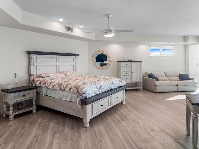 bedroom featuring ceiling fan, a textured ceiling, and light wood-type flooring