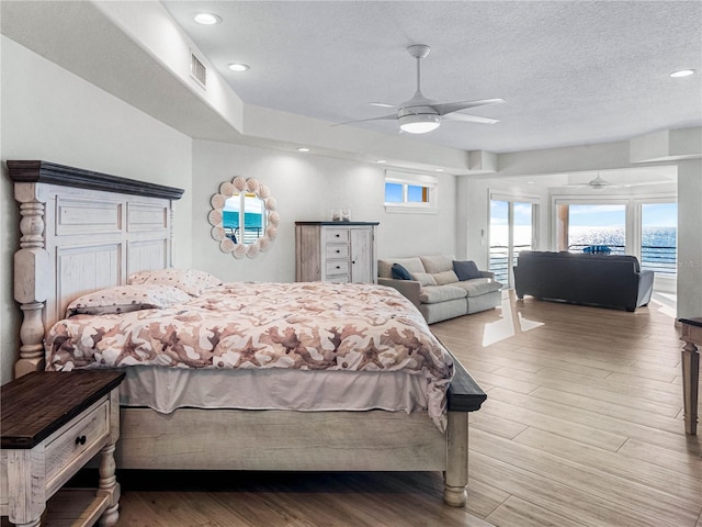 bedroom with multiple windows, hardwood / wood-style flooring, and a textured ceiling