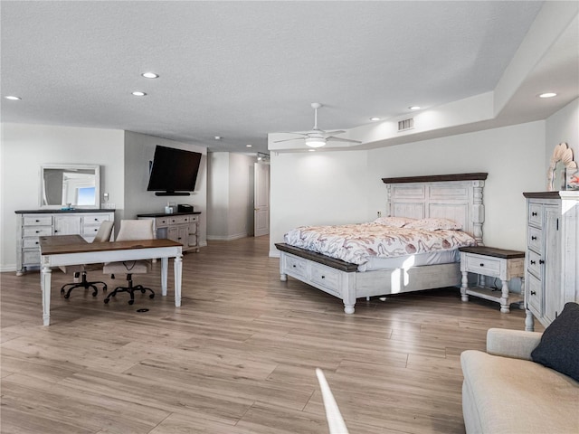 bedroom with ceiling fan, light hardwood / wood-style floors, and a textured ceiling