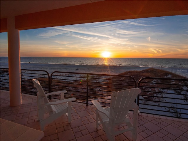 patio terrace at dusk with a water view and a beach view