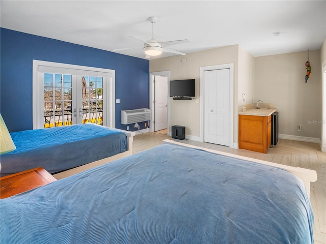 bedroom featuring a wall mounted air conditioner, sink, access to exterior, ceiling fan, and french doors