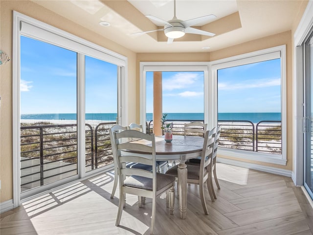 sunroom / solarium with ceiling fan, a beach view, and a water view