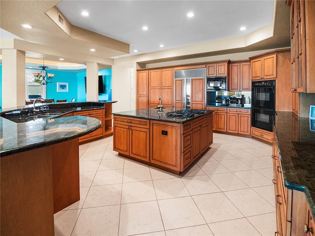 kitchen with black appliances, sink, dark stone counters, and a spacious island