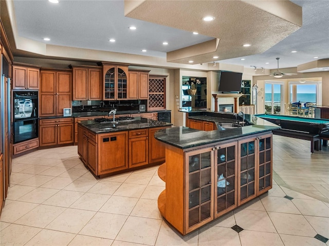 kitchen with a large island, sink, dark stone countertops, a textured ceiling, and light tile patterned flooring