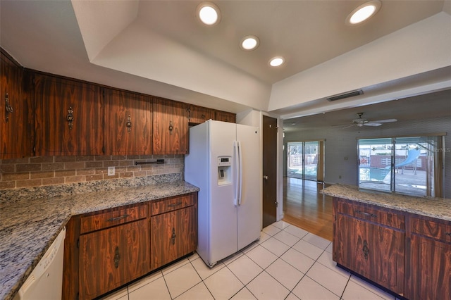 kitchen featuring stone countertops, light tile patterned floors, ceiling fan, white appliances, and backsplash