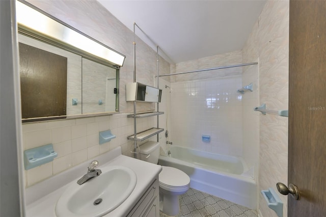 full bathroom featuring toilet, tile walls, vanity, tiled shower / bath combo, and decorative backsplash